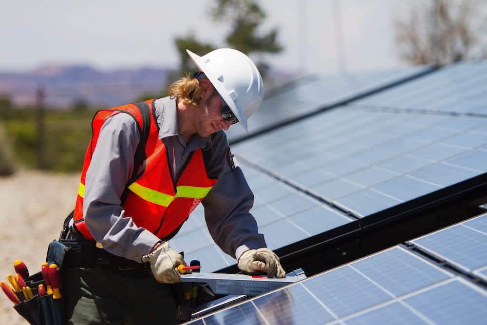 construction worker working on solar panel on solar farm