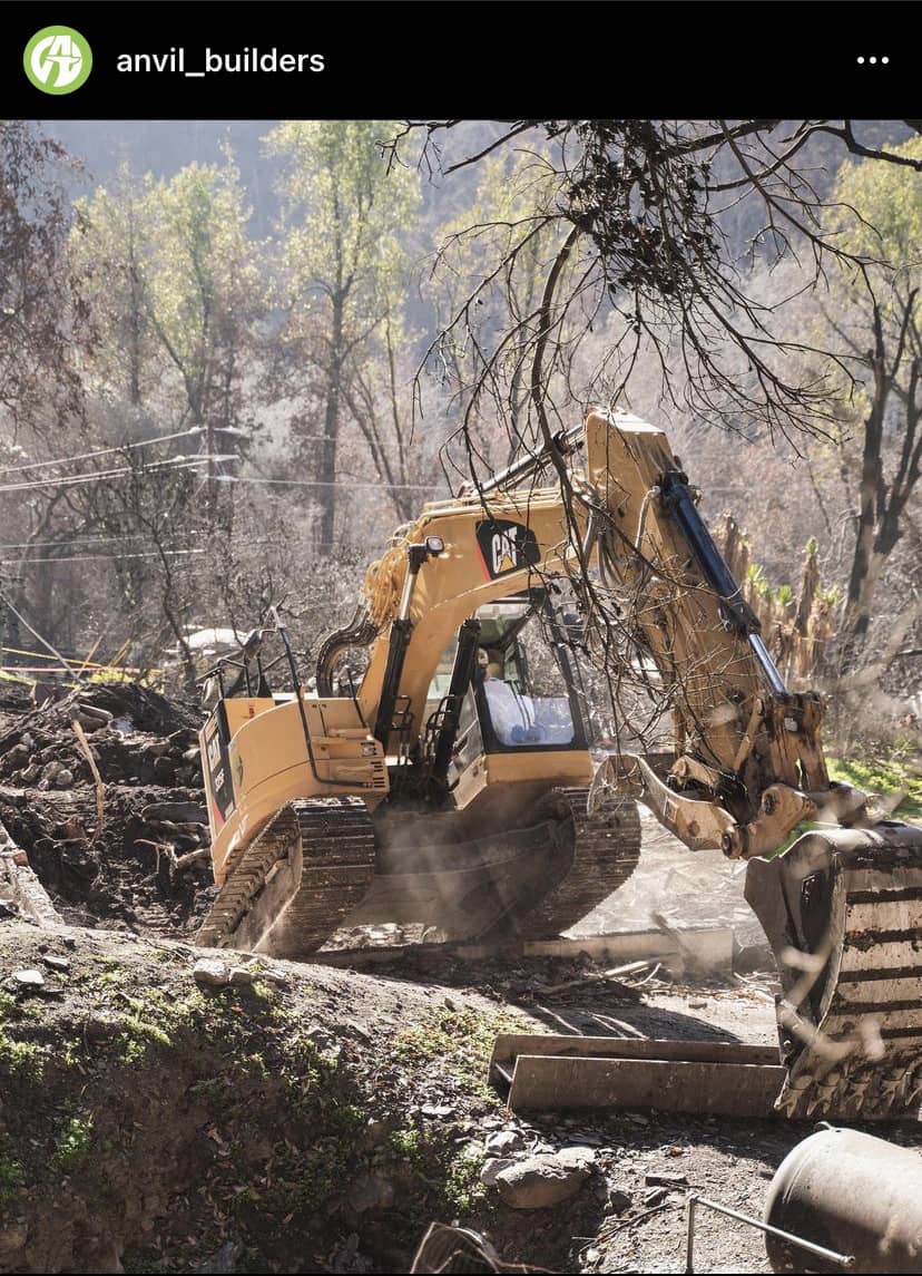 excavator driving through forest with large log