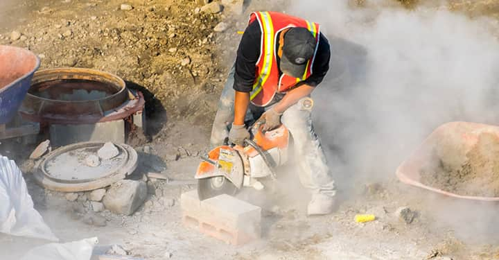 construction worker sawing in construction dust