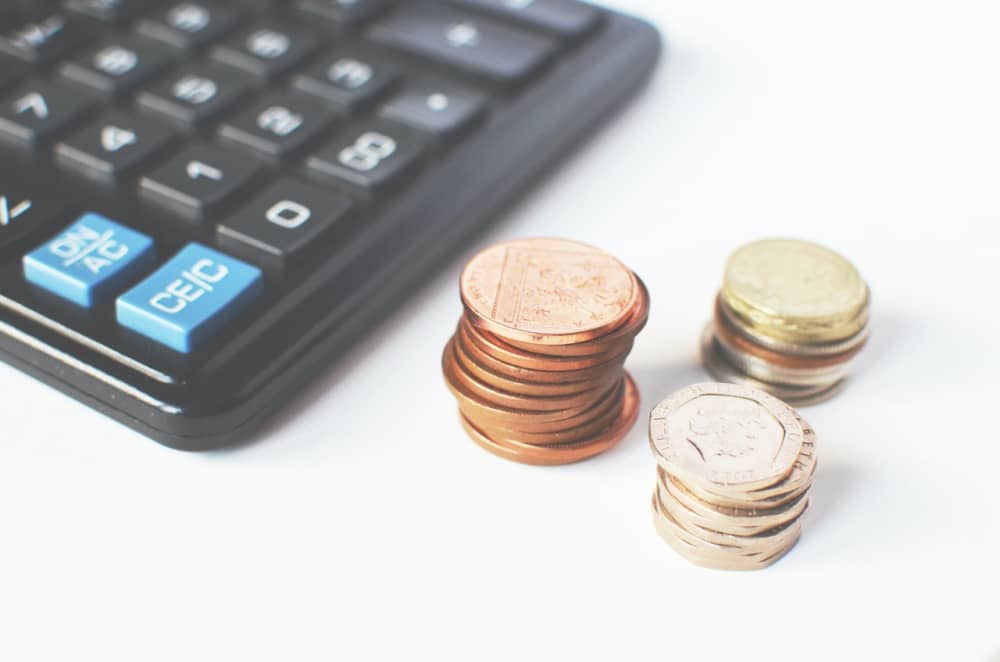 Three stacks of coins on a desk beside a calculator