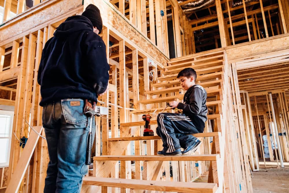 Father and son on a job site (wooden framed house). 