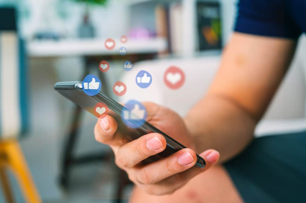 Construction worker scrolling on phone with likes and love icons bubbling up