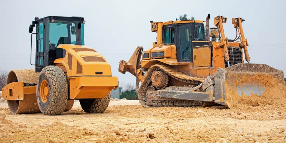 Soil compactor and dozer on a site clearing project