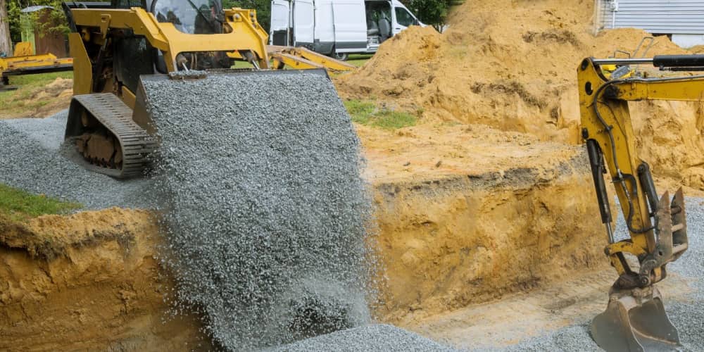 Compact track loader and mini excavator backfilling a foundation