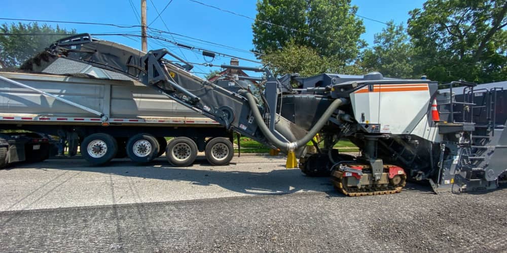 Cold planer milling asphalt into a dump truck on a roadwork project