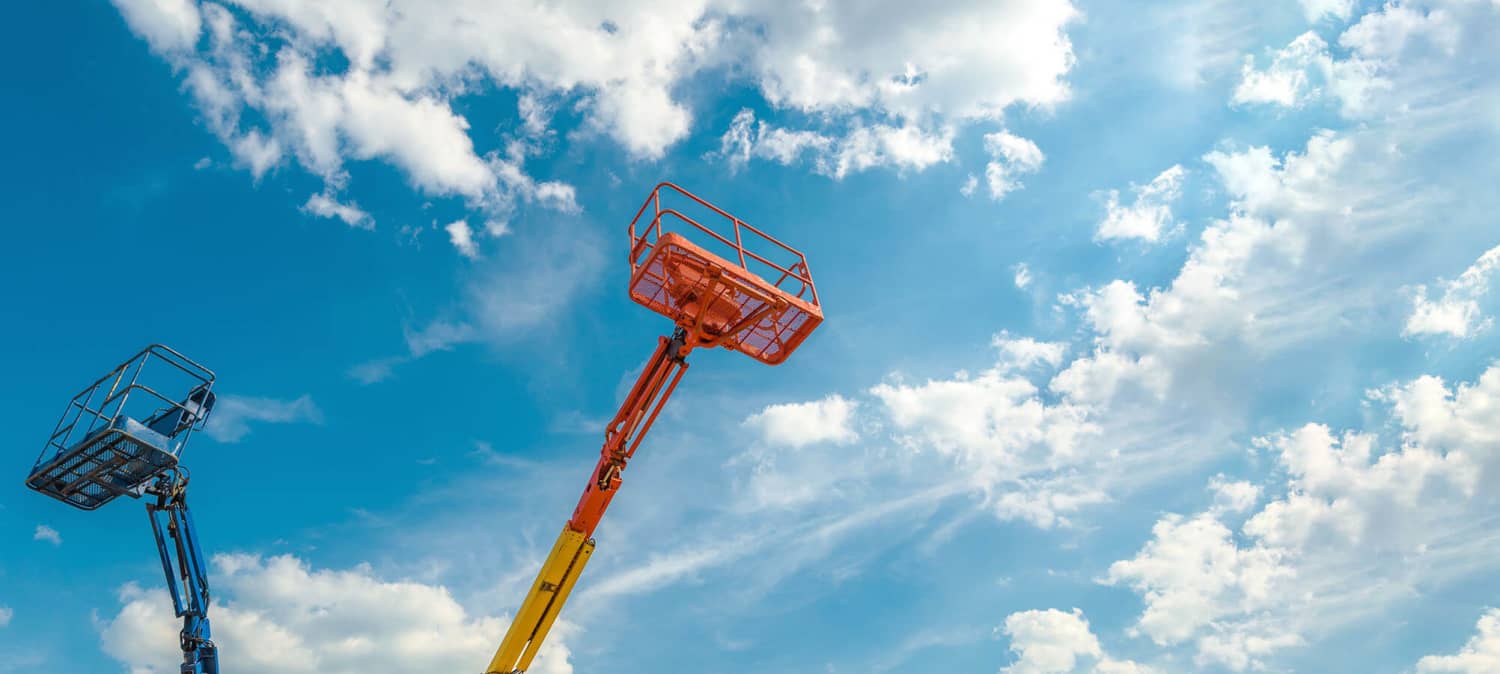 Boom lifts with blue sky and clouds in the background