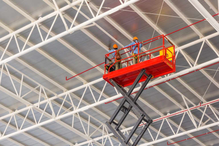 Two men in a scissor lift working in a warehouse 