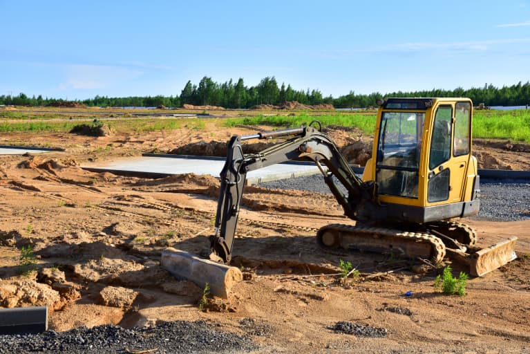 Mini Excavator with a bucket attachment working on a road project