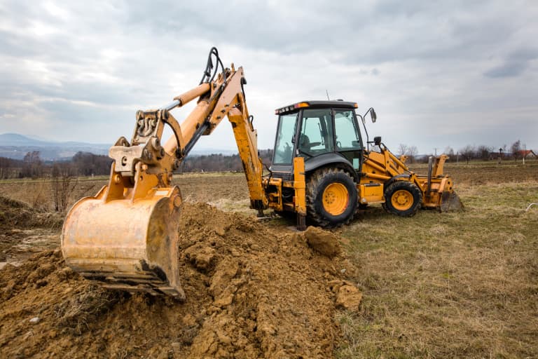 John Deere 310SK backhoe with a mini excavator and excavator sitting idle on a construction site that's being graded