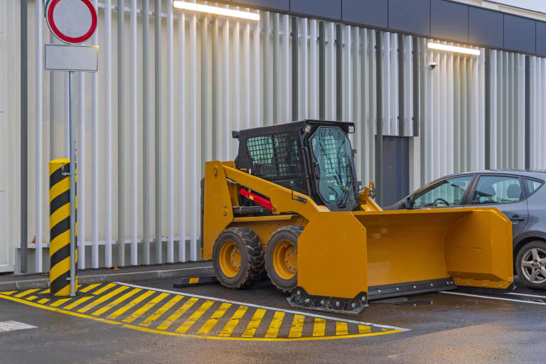 Skid steer with a snow pushing bucket sitting in a parking lot