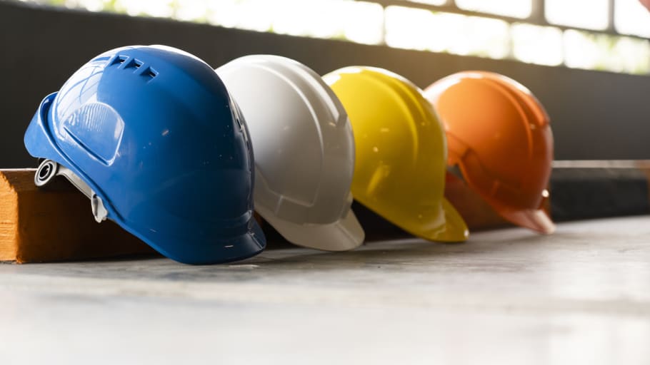 White, red, yellow, green, and blue hard hats lined up in organized lines