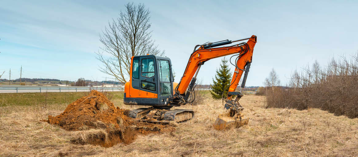 Mini excavator digging dirt in a field