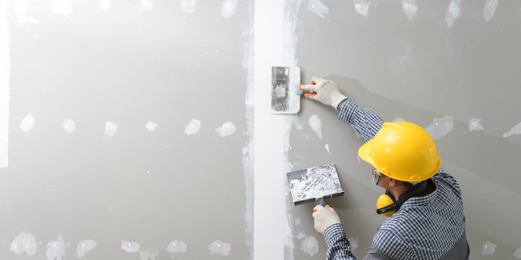 Worker patching Drywall