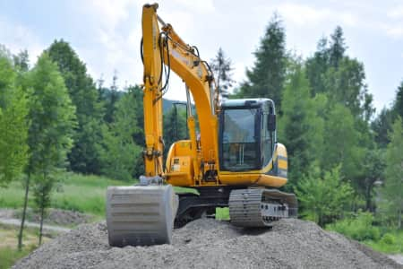 Yellow excavator on dirt pile in forest