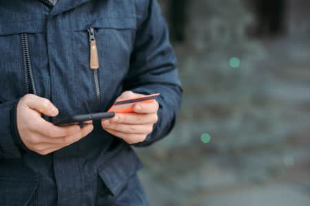 A person holding their phone in one hand and credit card in the other