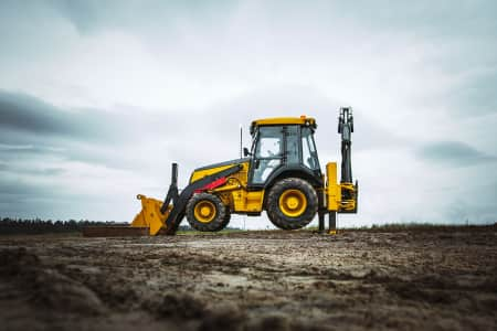 Backhoe loader with a bucket on a dirt road