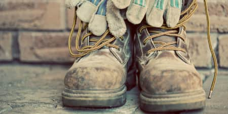 Work boots with work gloves hanging off of them