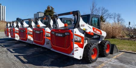 Five Bobcat S76 skid steers idle in a parking lot