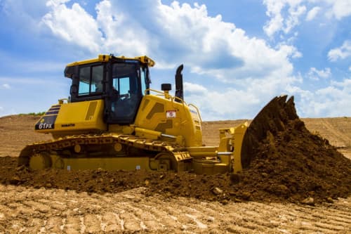 Komatsu dozer on a construction site pushing pile of dirt