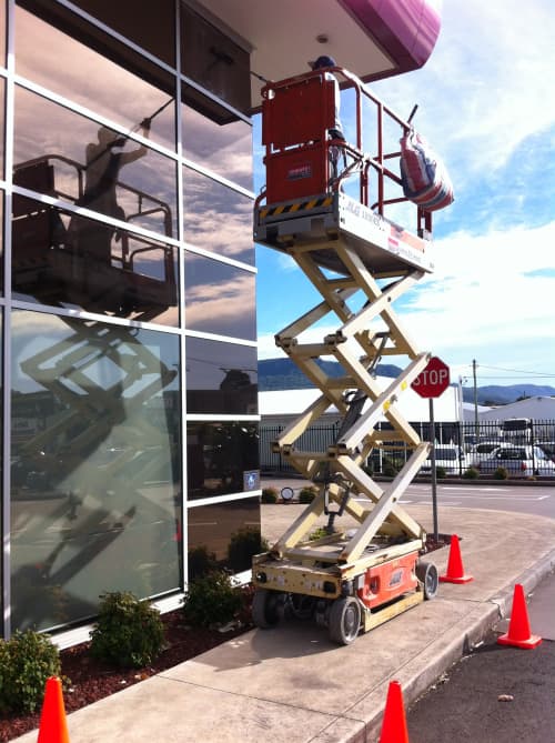 Window washer using a scissor lift to reach taller windows