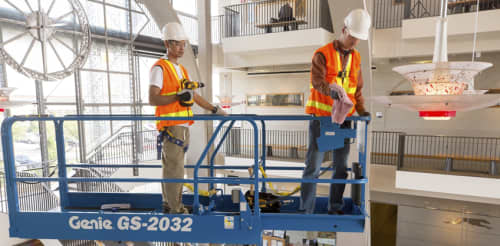 Two construction workers on a scissor lift wearing ppe