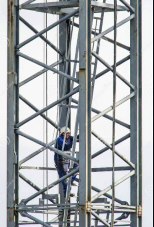 person climbing up the cage of a tower crane