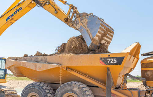 rock truck rental being loaded by excavator on construction site