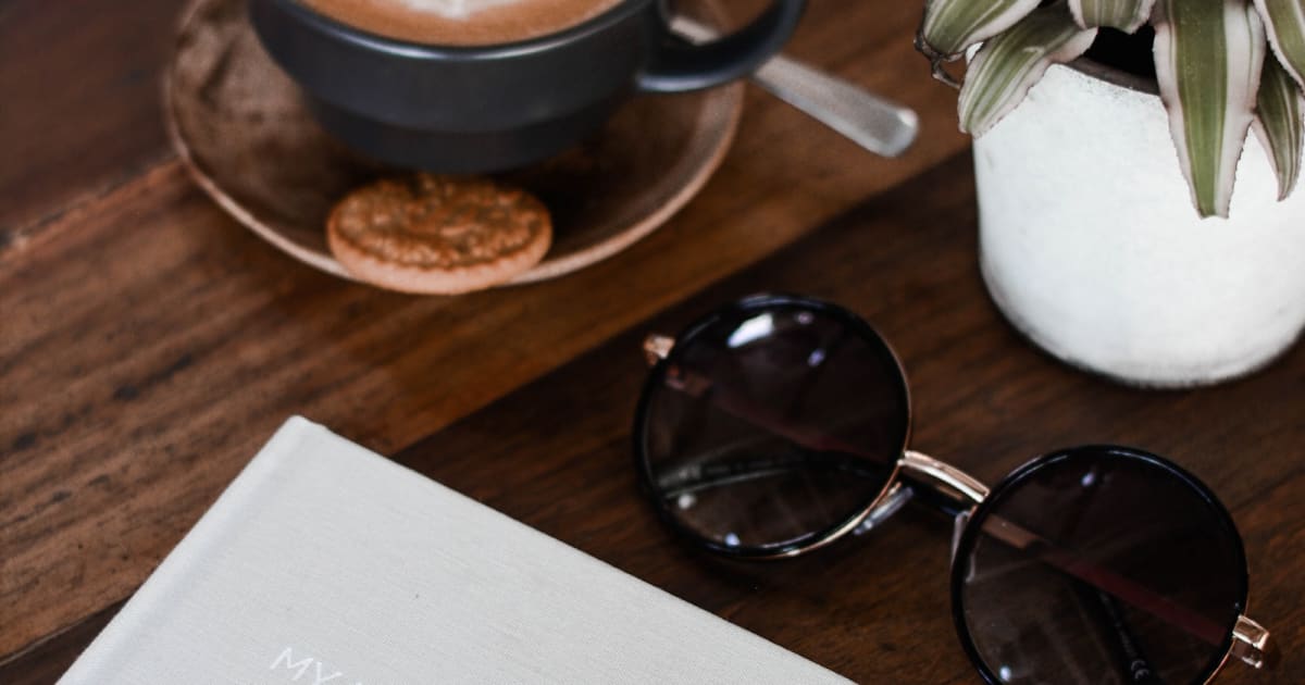 Coffee, sunglasses, and an open notebook on a table