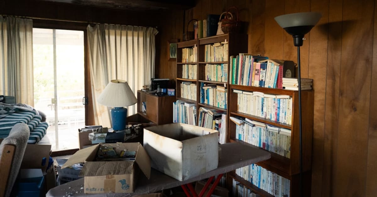 A cluttered storage room with bookshelves and packed boxes ready to be cleared out