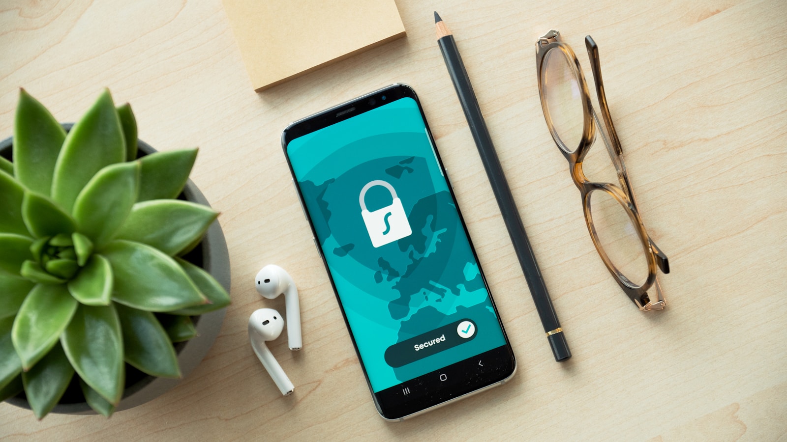 Phone displaying a lock symbol beside glasses and a plant