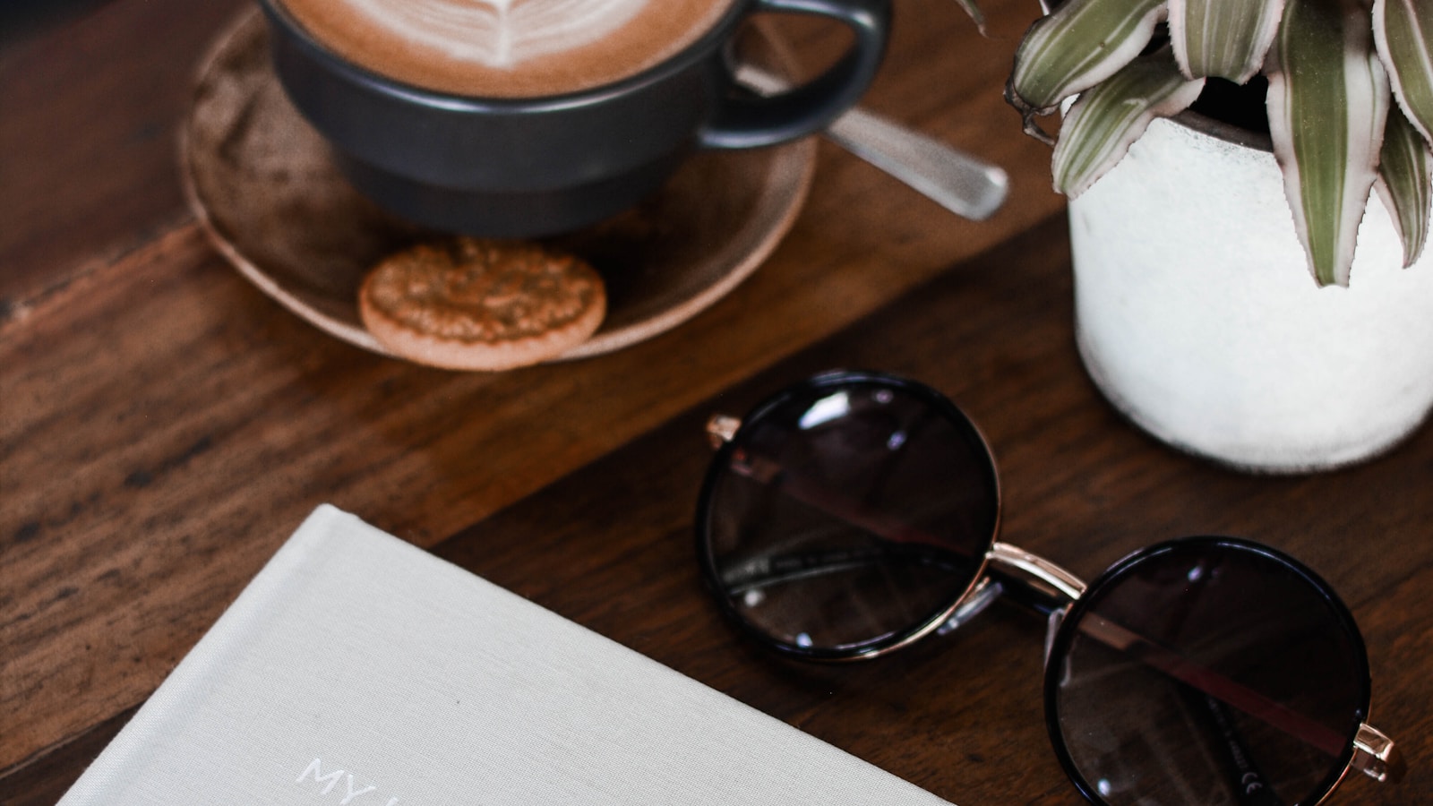 Coffee, sunglasses, and an open notebook on a table