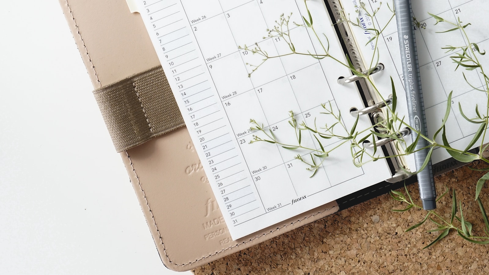Open paper planner with pen and botanical details