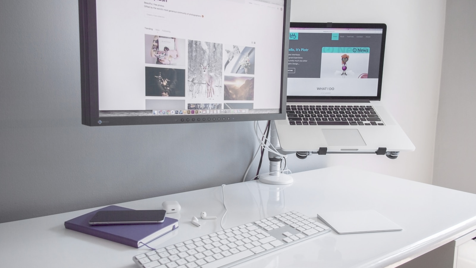 Clean white desktop with monitor, keyboard, and notebook