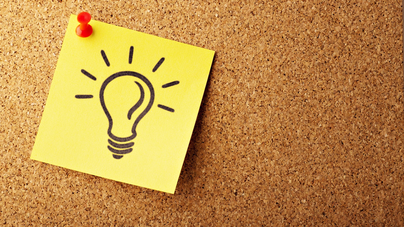 Yellow note with a hand-drawn light bulb pinned to cork