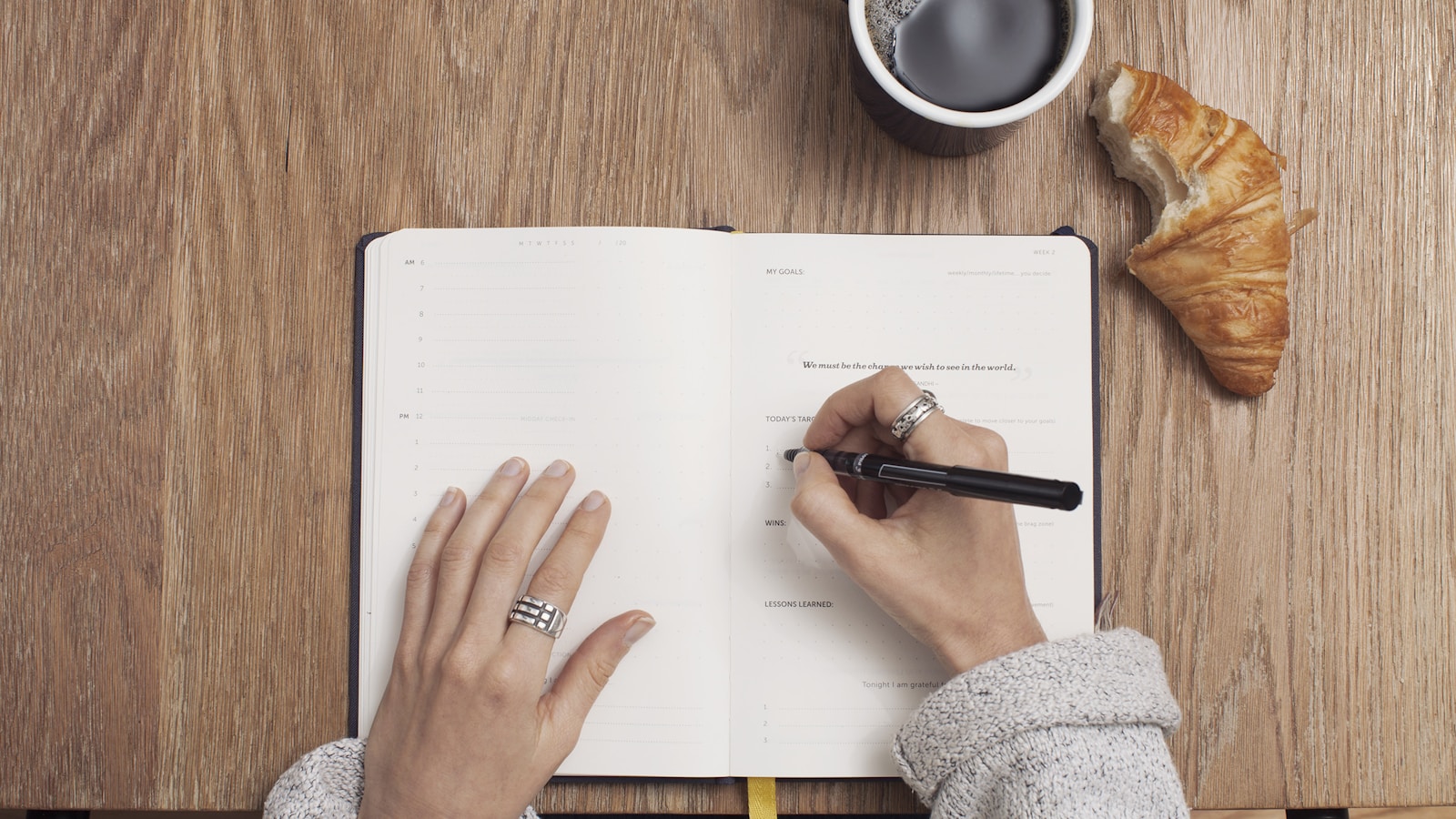 Hands writing in a blank notebook from above