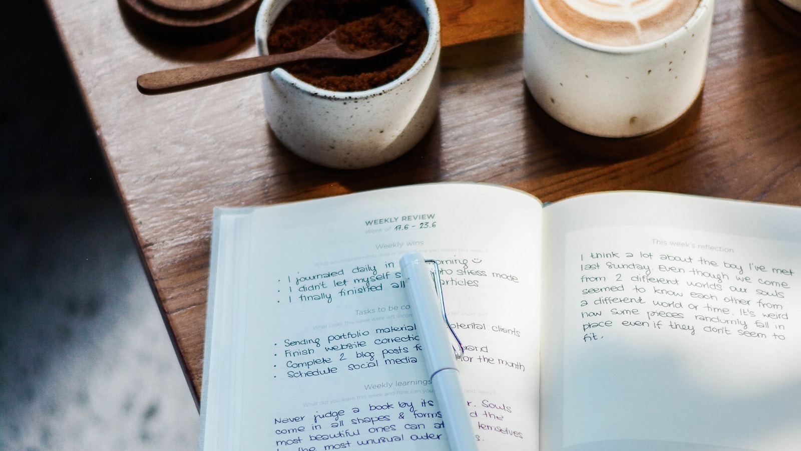 Open notebook beside coffee on a wooden table