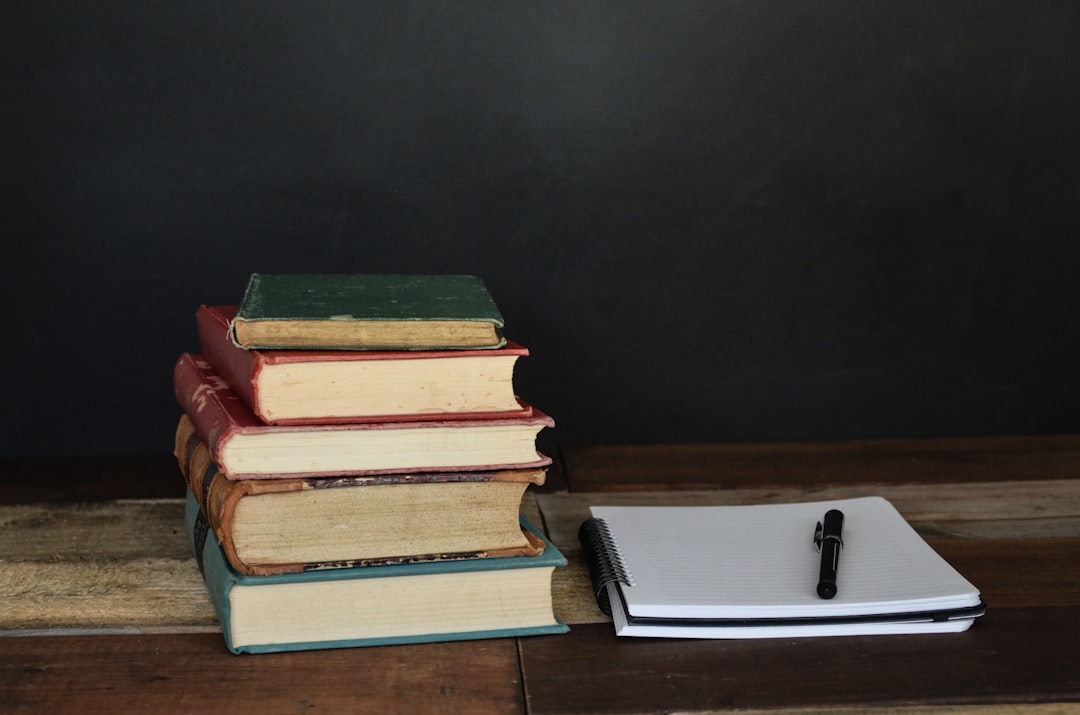 Stack of worn notebooks beside a clean modern notebook on a desk, representing the search for a permanent Evernote replacement rather than another temporary subscription