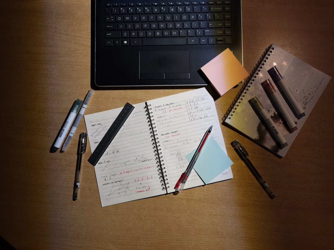 Desk with laptop, open notebook filled with handwritten notes, pens, and sticky notes, showing a practical second brain workspace