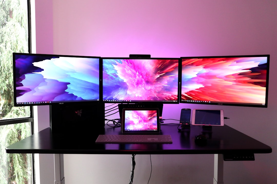 Multiple computer monitors on a desk displaying abstract colour gradients