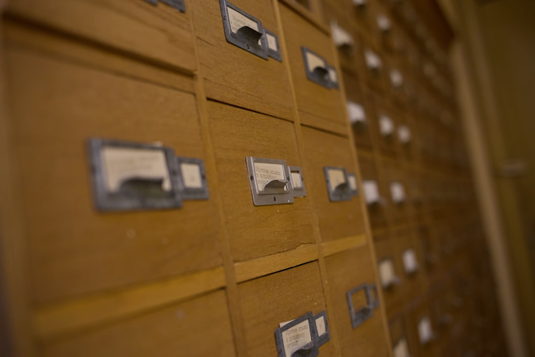 Wooden library card catalog with rows of small labelled drawers