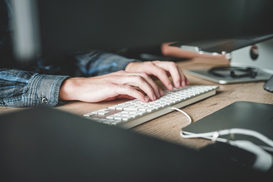 Close-up of hands typing on a keyboard at a desk