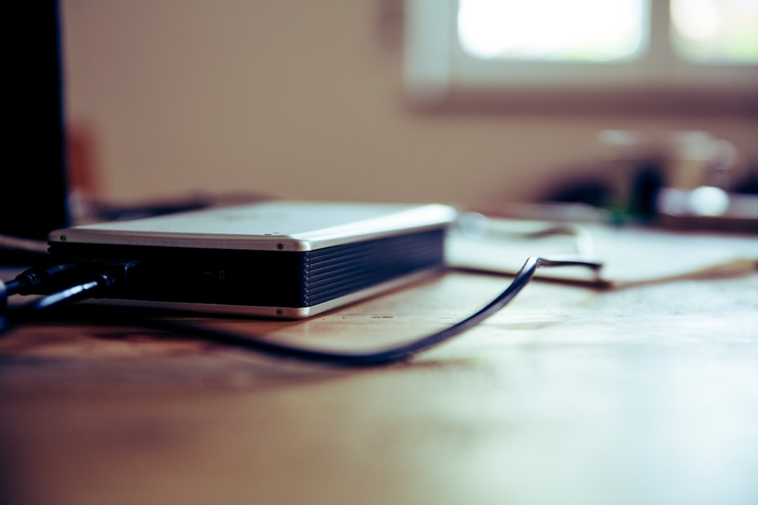A plain external drive with its connector cable resting on a desk
