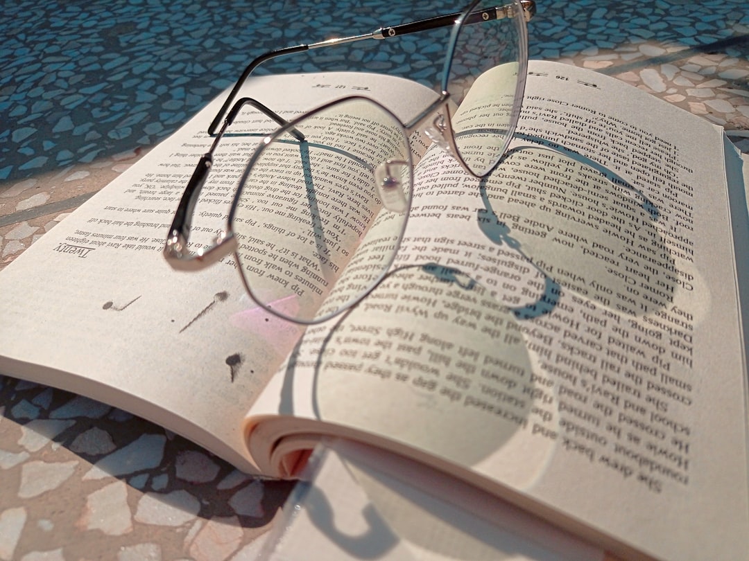 A pair of reading glasses resting on an open paperback book, representing careful reading and writing