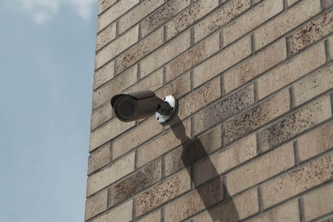 A security camera mounted on the corner of a brick building, representing monitoring and scoped access rather than a full, unrestricted view