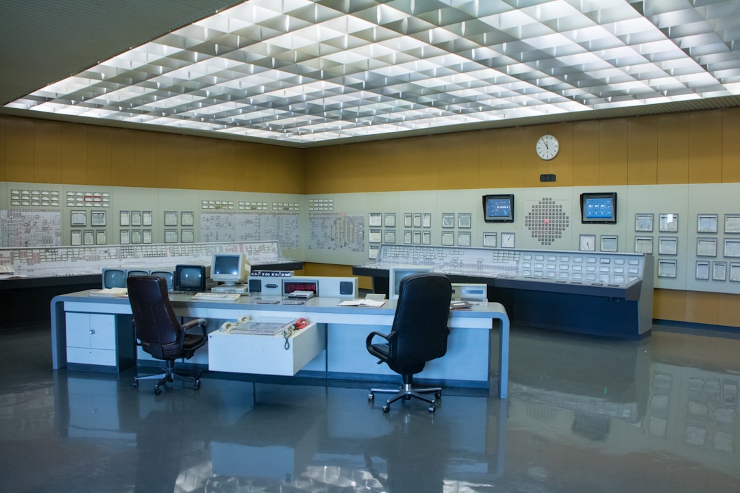 A retro control room with rows of desks, monitors, and wall panels under a grid of ceiling lights, representing a dashboard tracking many data streams at once