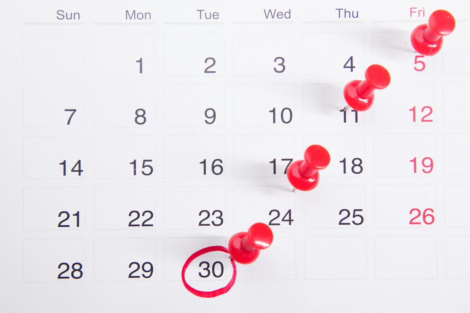 A wall calendar with red push pins marking a run of days, ending on a circled date