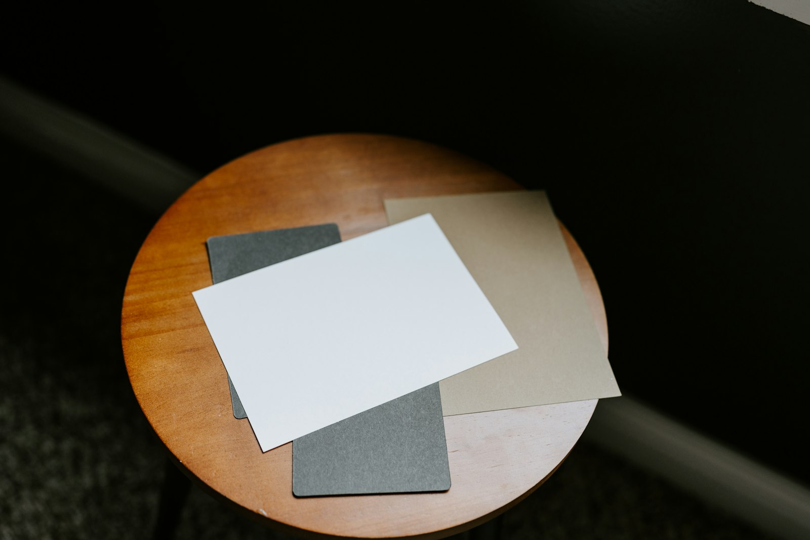 Blank white, gray, and tan sheets of paper stacked on a round wooden table