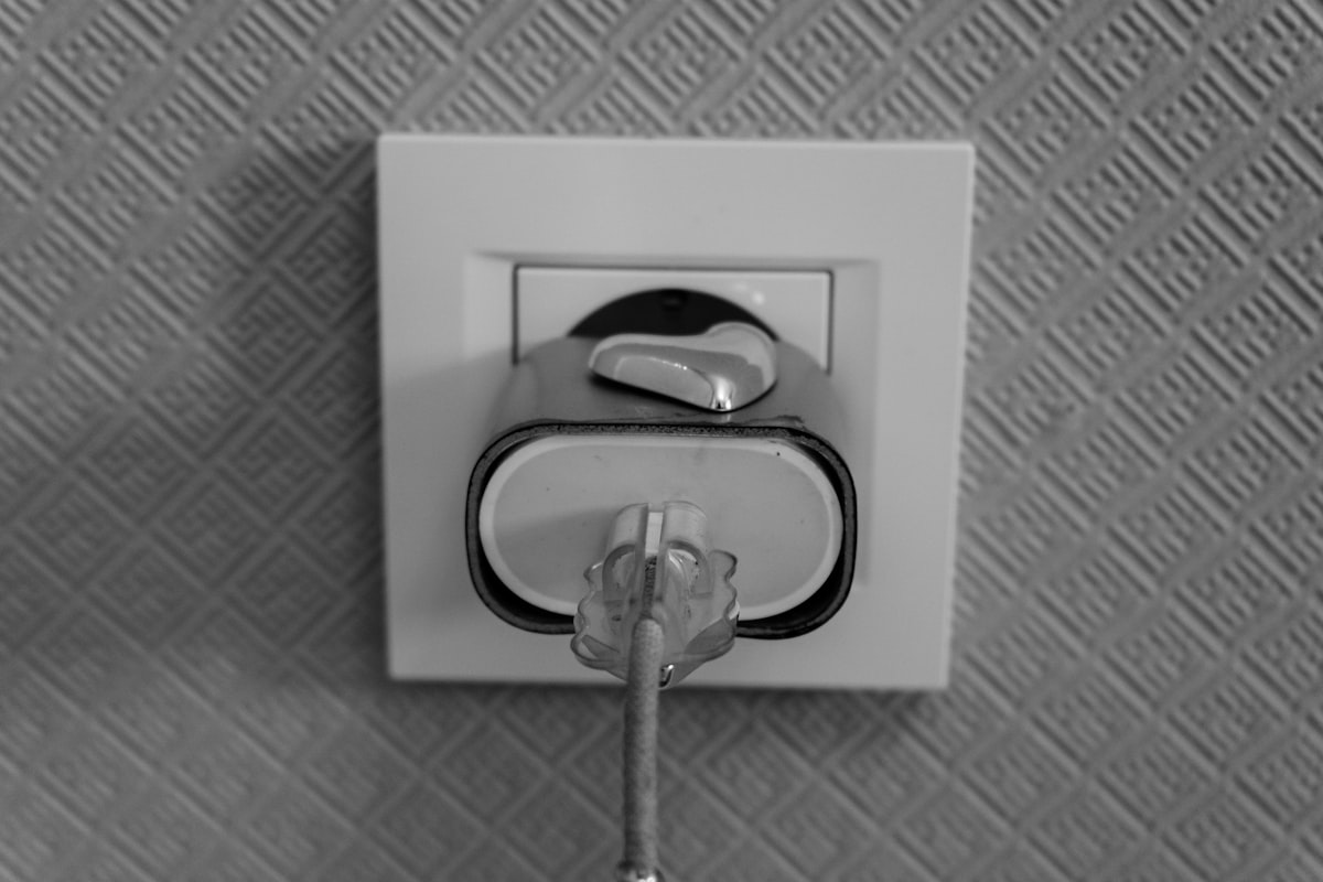 A black and white photo of an electrical plug inserted into a wall socket, representing connecting a new tool to an existing system