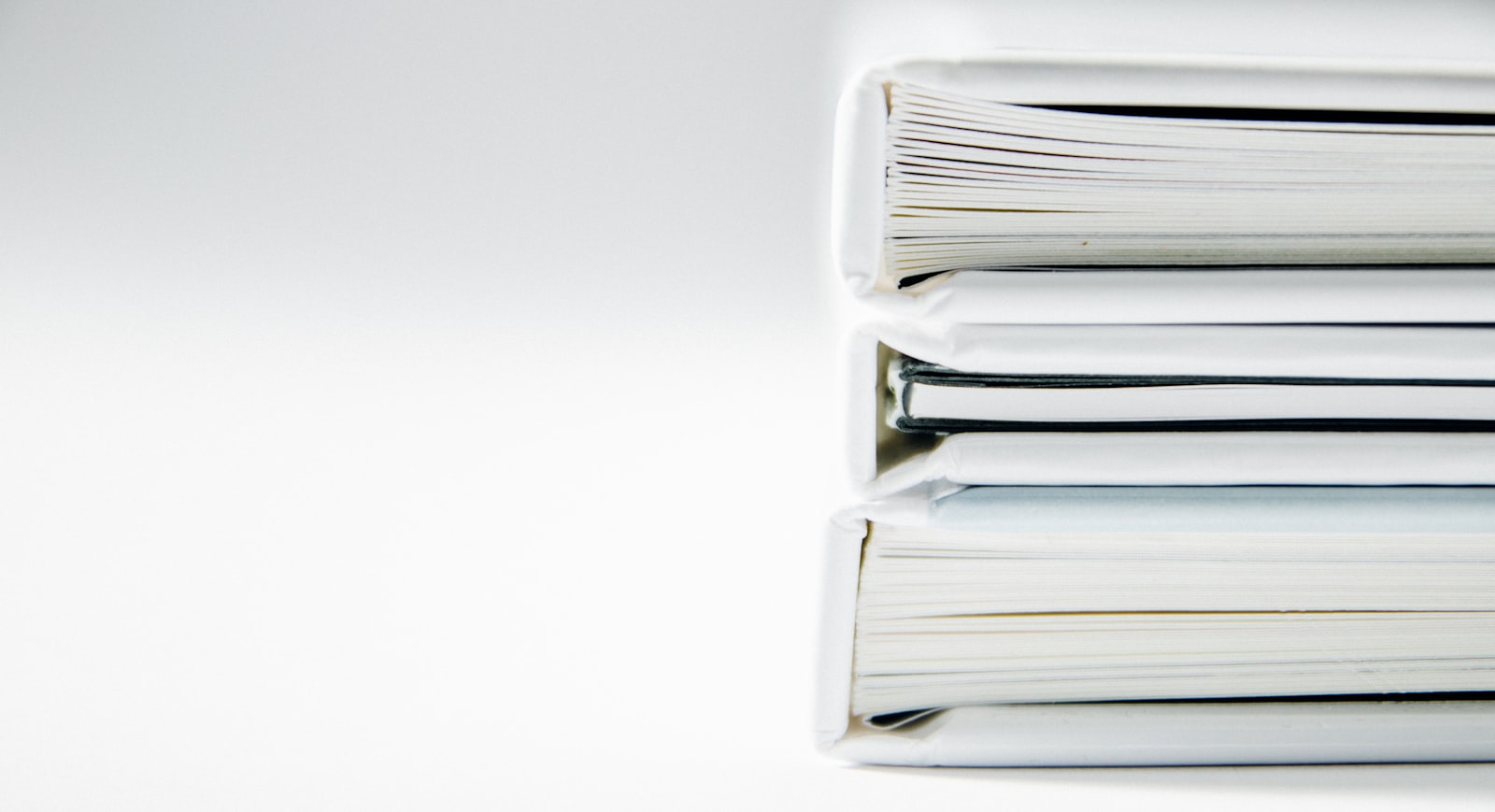 A stack of plain white binders viewed edge-on, each one separate and self-contained