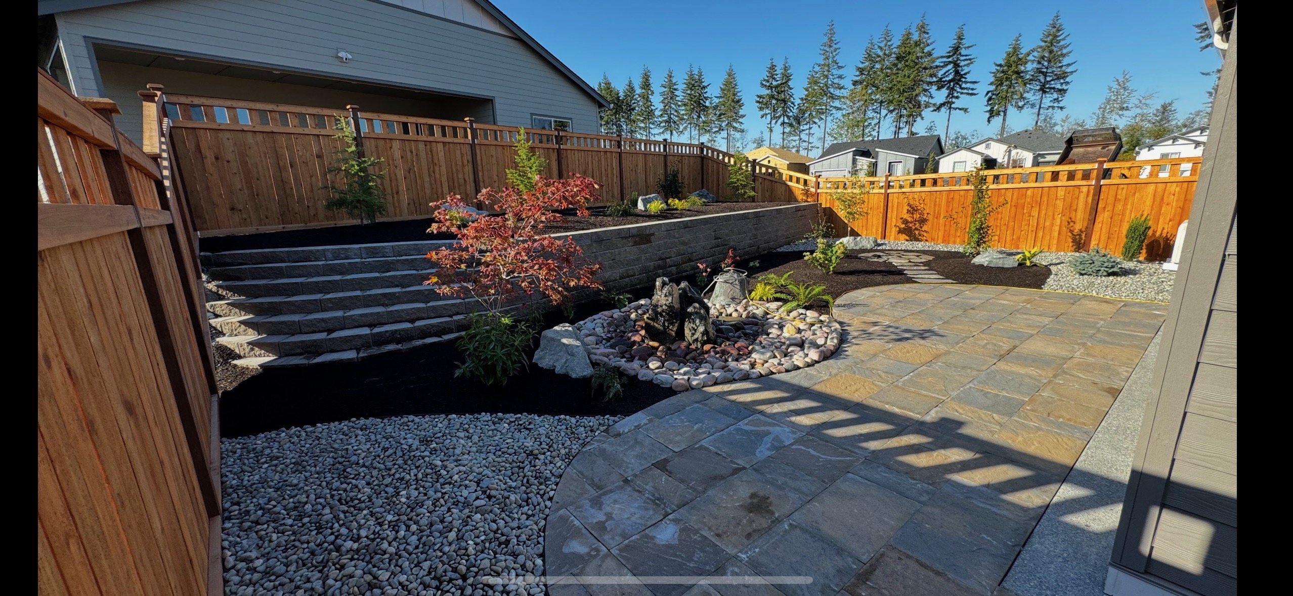 Patio with stone pavers, water feature, Japanese maple, and retaining wall by Todd's Nursery, Puyallup, WA